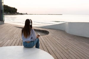 woman with headphones outside looking onto water