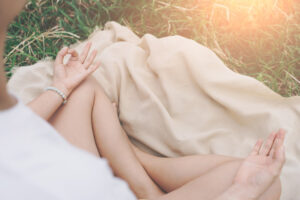 woman meditating on blanket in field